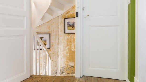 A staircase with white railings leading to a room with a white door and a green wall.