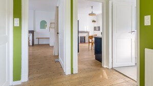 A hallway with wooden flooring leading to a kitchen area with a dining table and chairs.