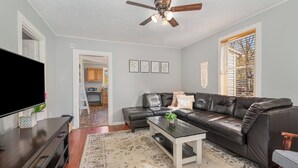 A modern living room with a leather sofa, a coffee table, a flat-screen TV, and a ceiling fan. - Cozy House, Pets Welcome, Minutes from Harrisburg (Duncannon)