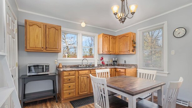 A kitchen with wooden cabinets, a microwave, a sink, and a dining table with chairs. - Cozy House, Pets Welcome, Minutes from Harrisburg (Duncannon)