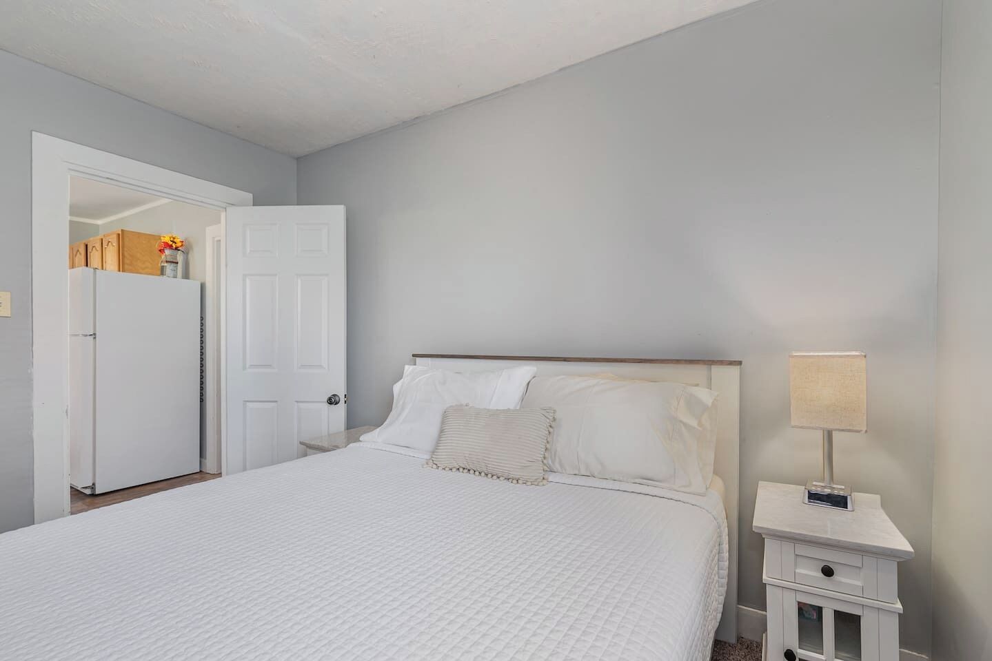 Une chambre à coucher comprenant un lit, une table de chevet, une lampe et une porte donnant sur un placard.