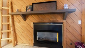 Une cheminée avec un manteau en bois et un tableau encadré au-dessus.