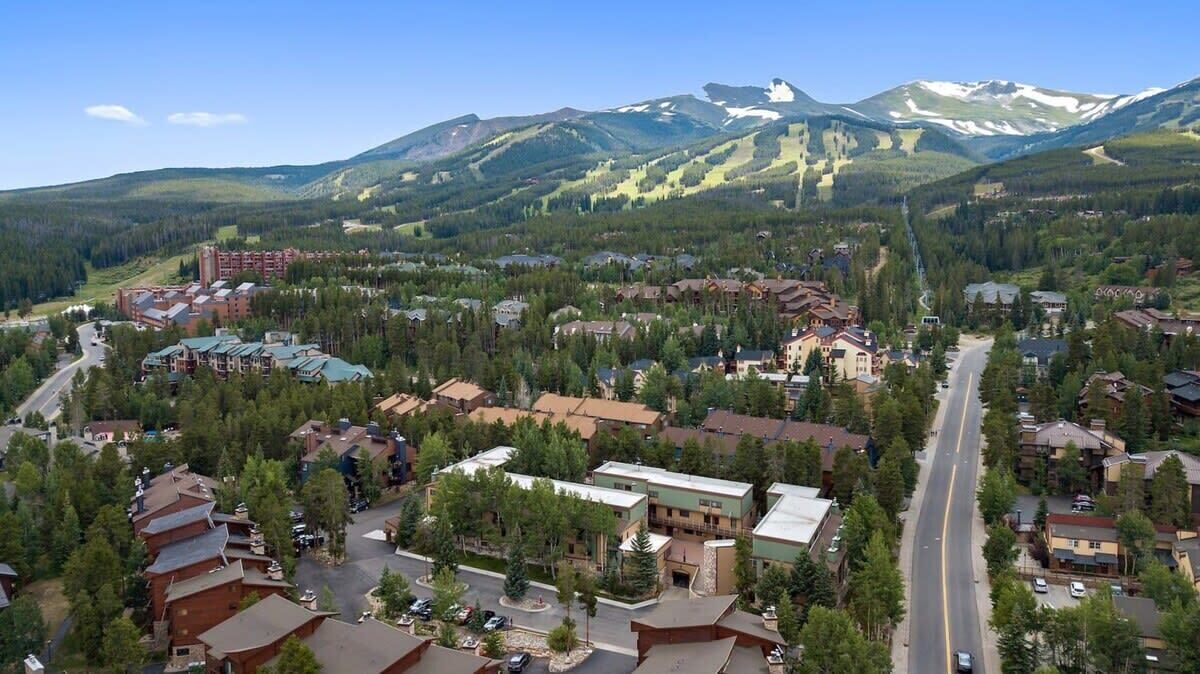 A town with a central road, buildings, and a mountain range in the background.