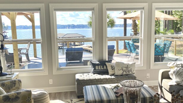A cozy living room with a view of a dock and water, featuring a sofa, ottoman, and decorative pillows. - Lake Greenwood, Big Water and Sunset Views (Chappells)