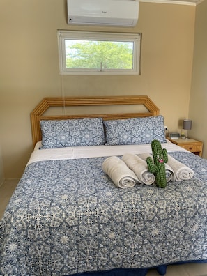 A bedroom with a bed, a window, a nightstand, and a cactus decoration. - LiCe 's Garden Aruba (Paradera)