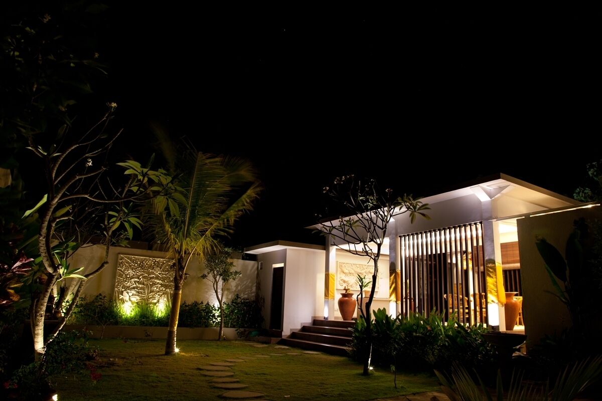 A modern house with a well-lit entrance, a small garden, and a pathway leading to the door.