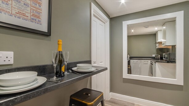 A modern kitchen with a grey wall, white cabinets, and a large mirror. - Gillygate Boutique Apartment - sleeps 4 guests  in 1 bedroom (York)