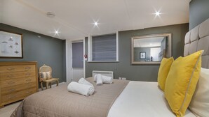 A bedroom with a large bed, a wooden dresser, a chair, and a window with blinds. - Gillygate Boutique Apartment - sleeps 4 guests  in 1 bedroom (York)