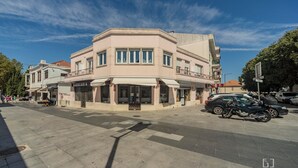 A multi-story building with a corner entrance, a visible storefront, and a parked motorcycle. - MouraLua (Sintra)