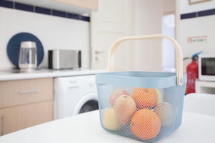 A kitchen with a blue basket containing oranges on a white countertop.