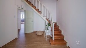 A staircase with wooden steps and white railings, leading to a door marked with an emergency exit sign. - MouraLua (Sintra)