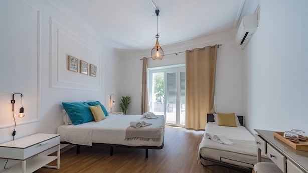 A modern hotel room with a wooden floor, two beds, a desk, and a large window with curtains. - MouraLua (Sintra)