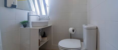 A small bathroom with a toilet, sink, and a mirror.