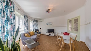 A modern living room with a sofa, chairs, a dining table, and a TV. - MouraLua (Sintra)