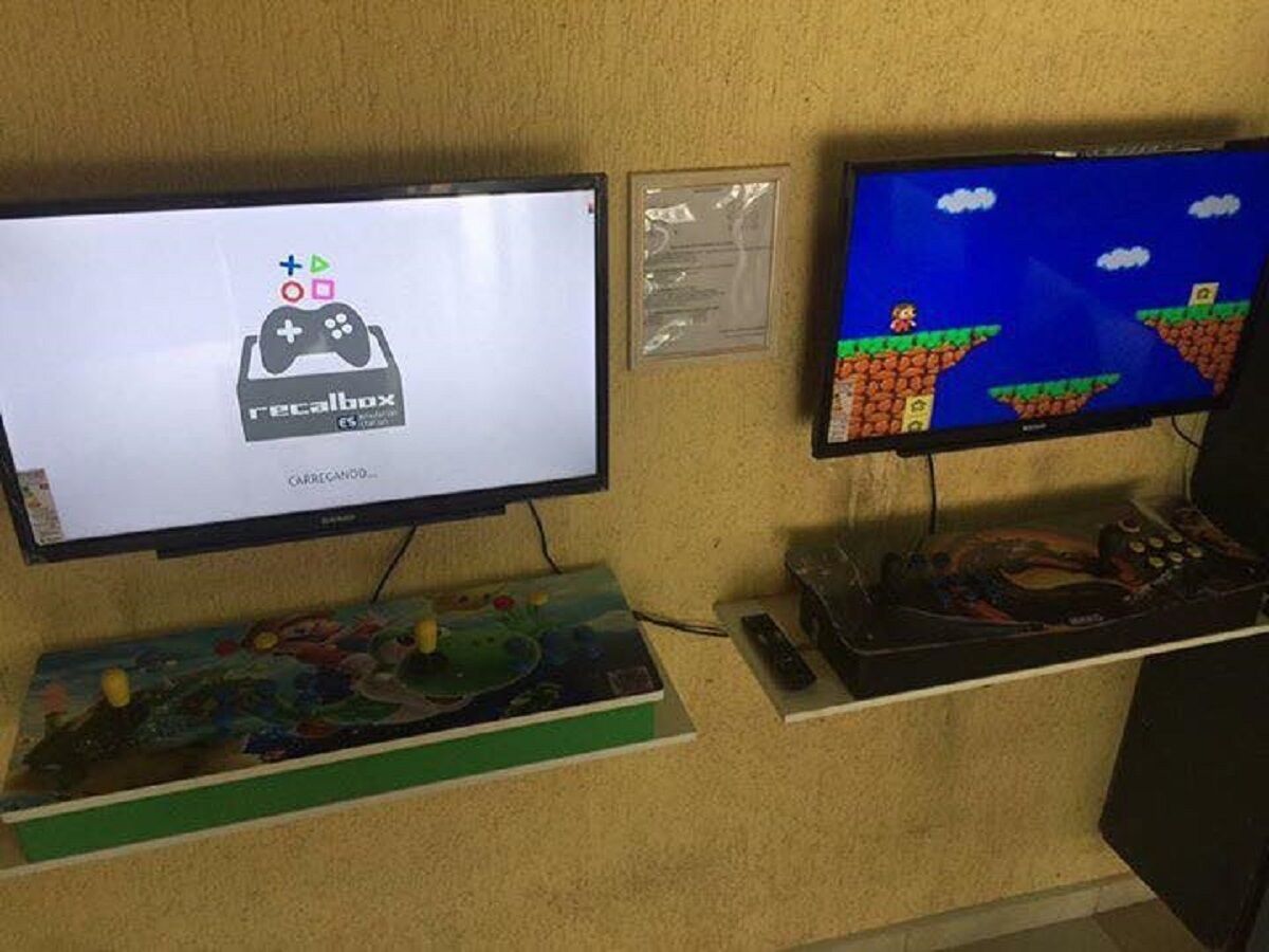 Two monitors displaying video games, a keyboard, and a mouse on a shelf.