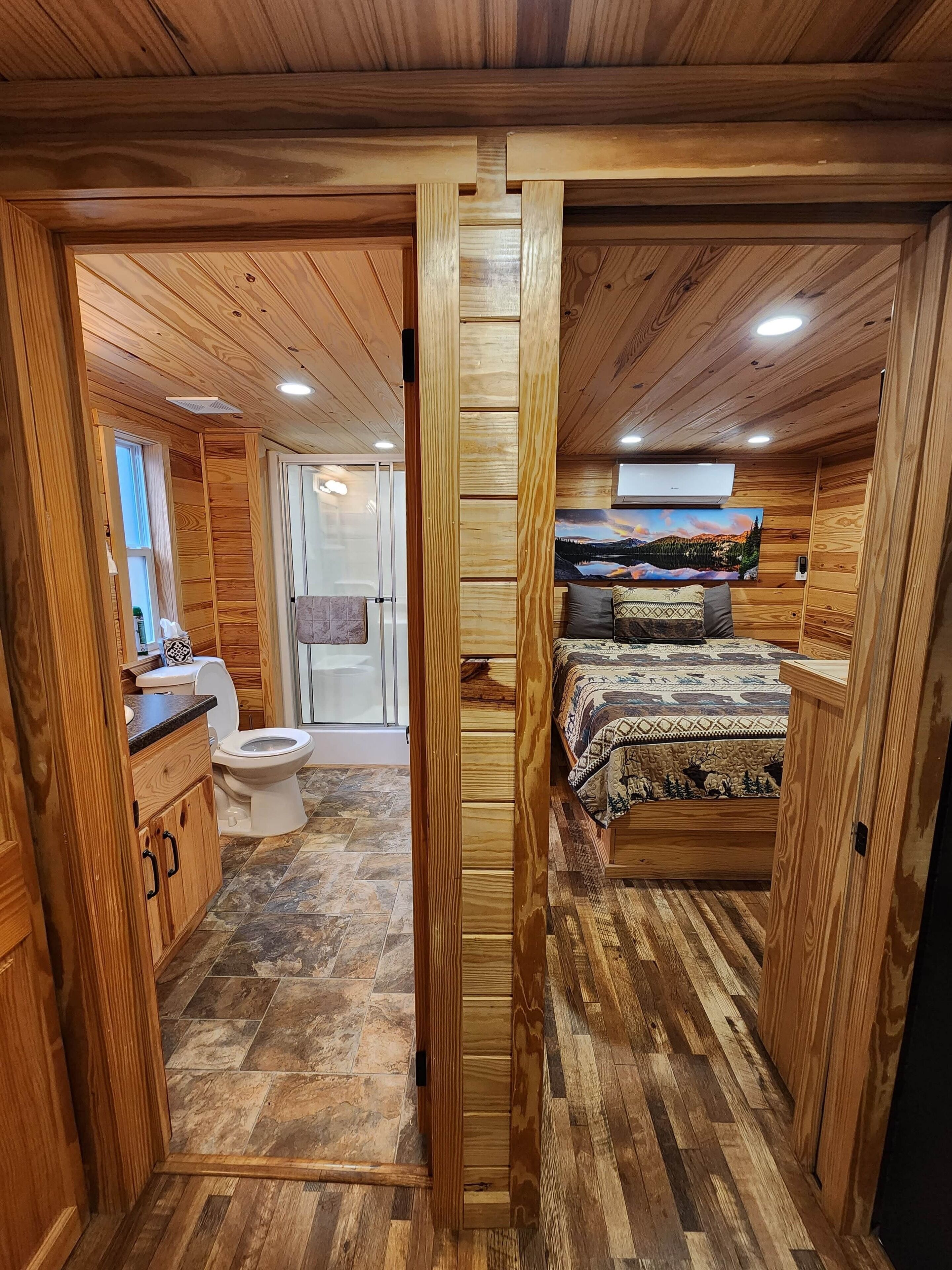 A compact, wood-paneled room with a bed, a toilet, and a small kitchenette.