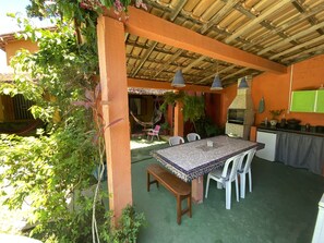 Una terrazza esterna con tavolo e sedie in pietra, un'amaca e un barbecue.