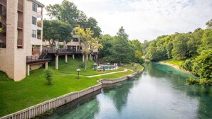 A riverside view of a multi-story building with a swimming pool and a deck area.