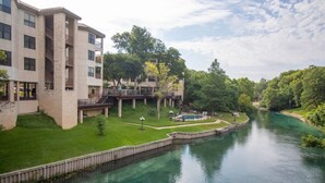 A riverside hotel with a swimming pool, a deck, and a view of the river.
