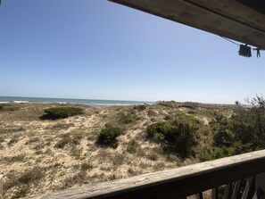 A beach view with a wooden deck and a clear sky.