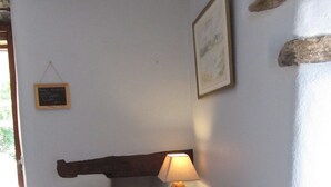 Una habitación con dos sillones amarillos, una mesita de madera con una lámpara, un cuadro enmarcado en la pared y un letrero en una pizarra.
