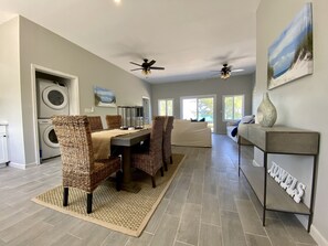 Ein großzügiges Wohnzimmer mit Essbereich, großen Fenstern und einem Deckenventilator.