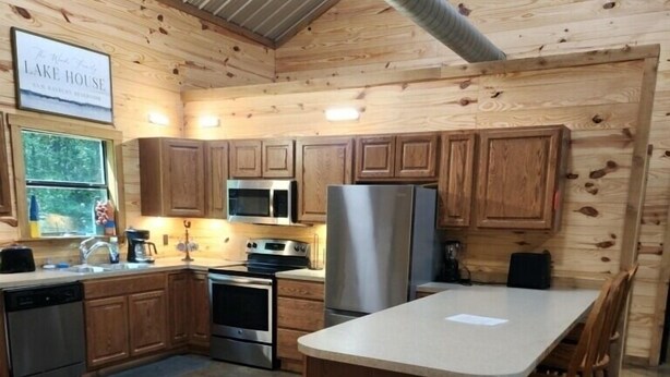Une cuisine moderne avec des meubles en bois, des appareils électroménagers en acier inoxydable et un îlot central doté de tabourets de bar.