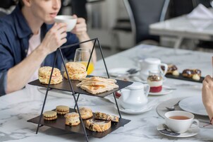 Una escena de desayuno con una bandeja de pasteles, una taza de té y un vaso de jugo de naranja sobre una mesa de mármol.
