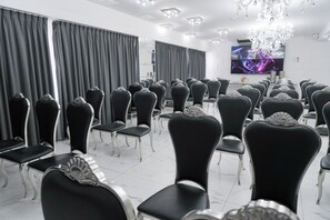 A conference room with rows of black chairs, a chandelier, and a flat-screen TV on the wall. - Ker San Telmo Hotel (Buenos Aires)