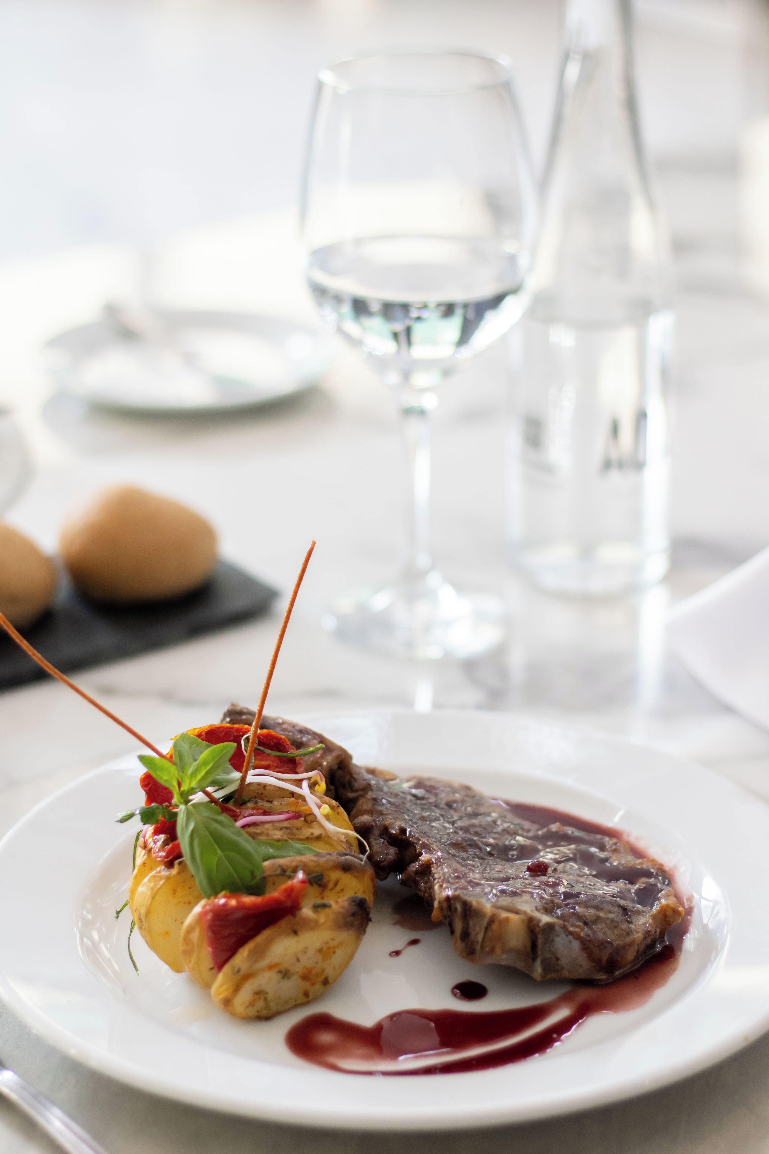 Un plato con un bistec y verdura rellena, un vaso de agua y una botella sobre una mesa.