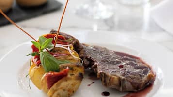 Un plato con un bistec y verdura rellena, un vaso de agua y una botella sobre una mesa.