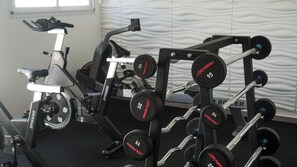 Un gimnasio con diferentes equipos de ejercicio, incluyendo mancuernas y una bicicleta estática.