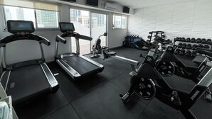 Un gimnasio con cintas de correr, bicicletas estáticas y pesas.