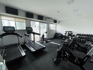 A gym with treadmills, a spinning machine, and dumbbells. - Ker San Telmo Hotel (Buenos Aires)