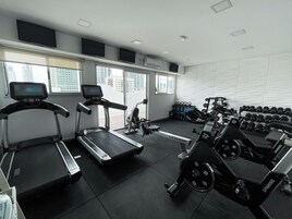 Un gimnasio con cintas de correr, bicicletas estáticas y pesas.