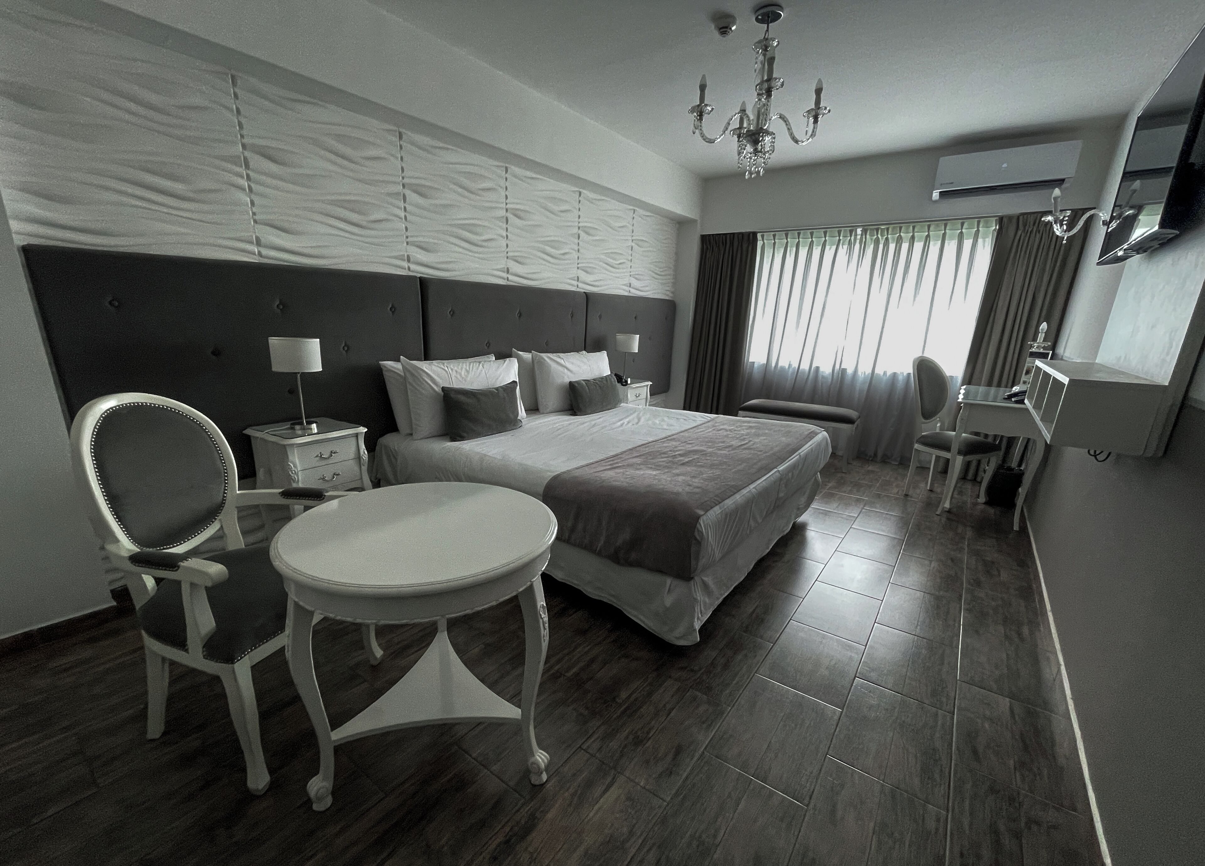 Habitación de hotel con una cama grande, un escritorio, una silla y una mesita.