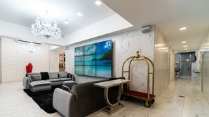 Una sala moderna con un sofá seccional gris, una mesita redonda y un carrito dorado.