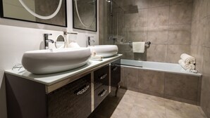 Un baño moderno con dos lavamanos amplios, una ducha con cerramiento de vidrio y una bañera independiente.