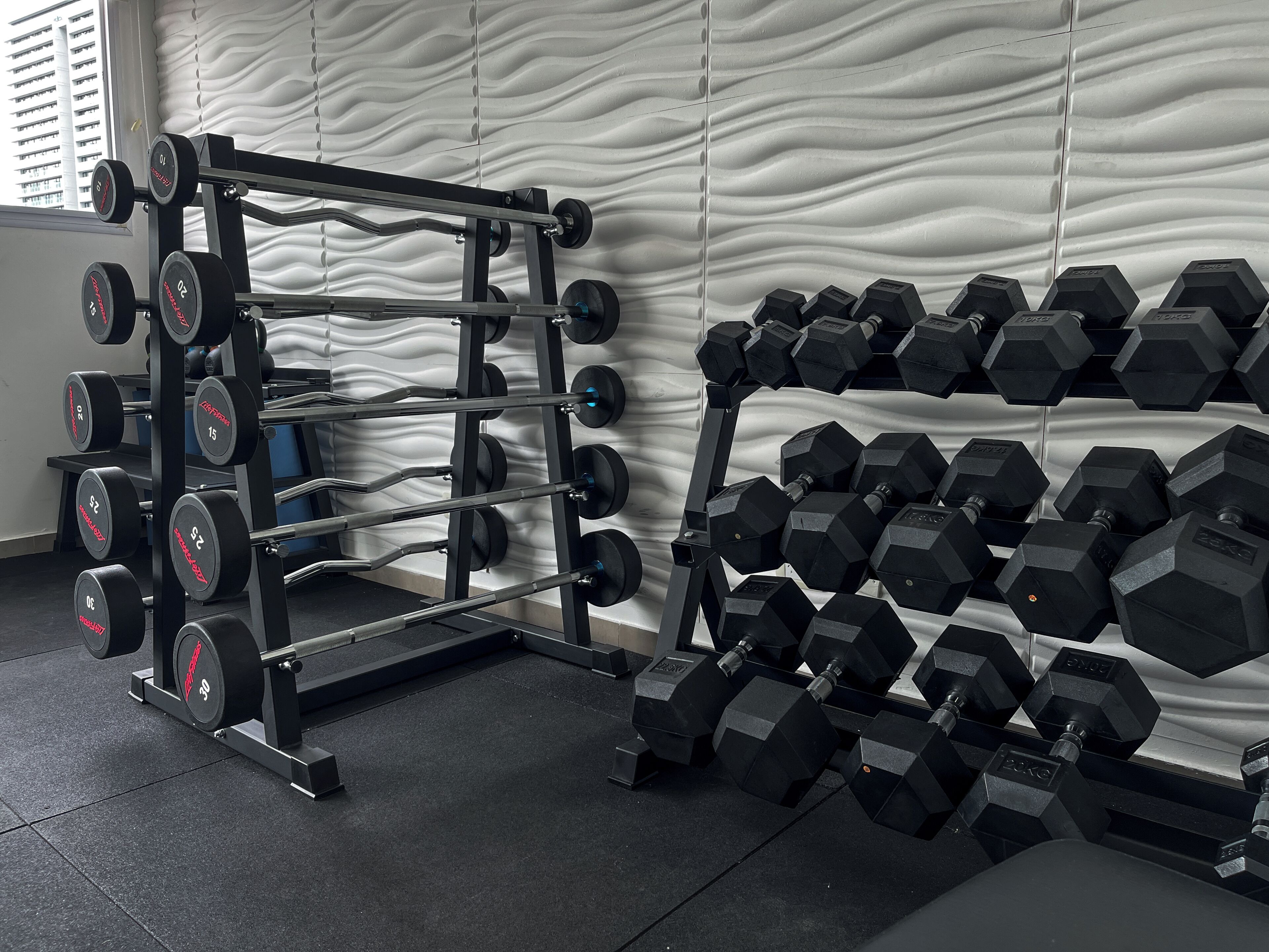 Un gimnasio con una estructura para pesas y varios juegos de mancuernas.
