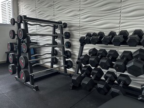 Un gimnasio con una estructura para pesas y varios juegos de mancuernas.