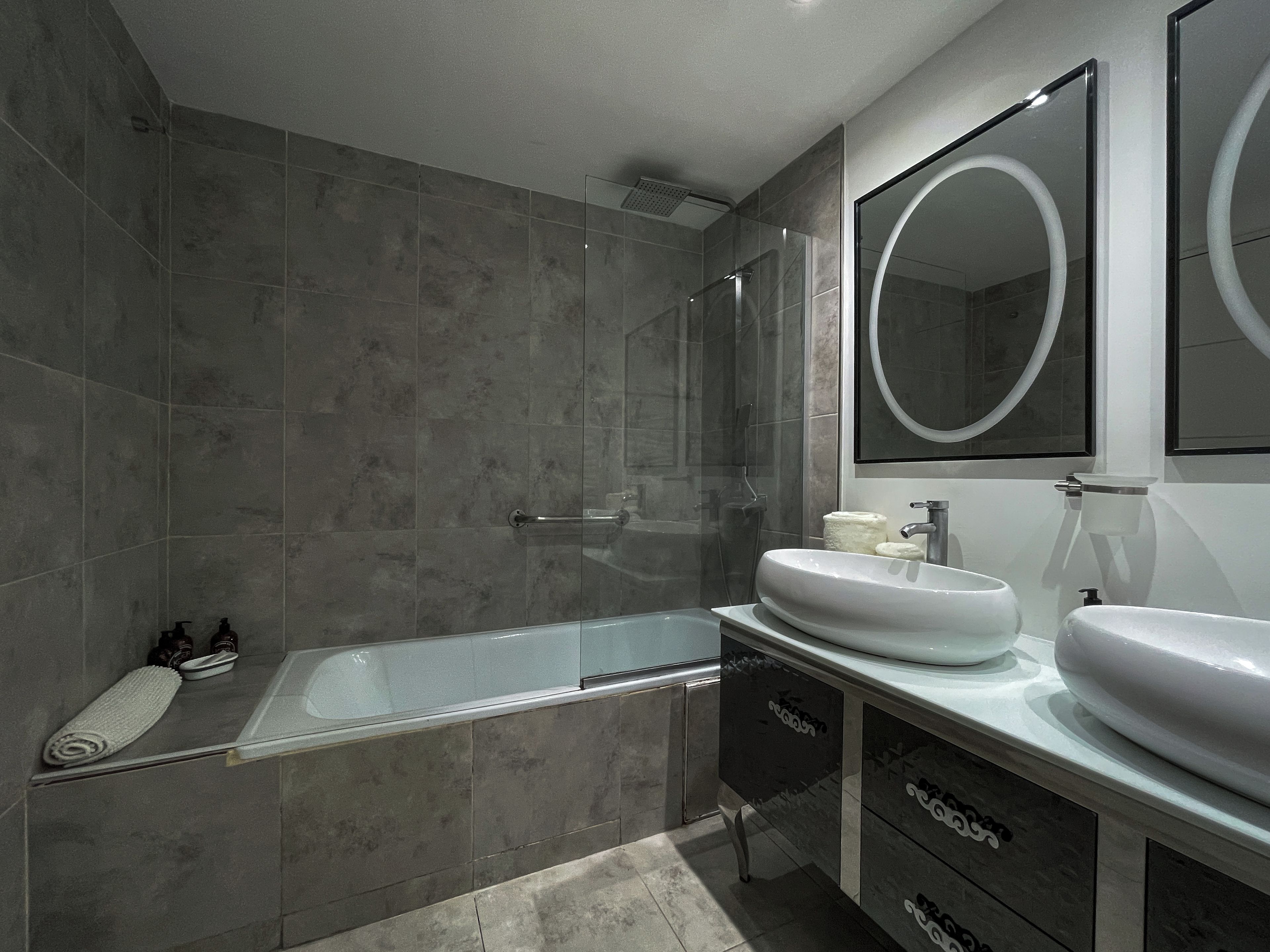 A modern bathroom with a glass-enclosed shower, a large mirror, and a vanity with two sinks.