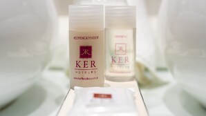 Dos productos para el cuidado de la piel etiquetados con 'KER' sobre una bandeja en un hotel.