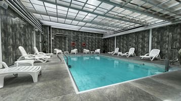Una piscina al aire libre, sillones reclinables de piscina
