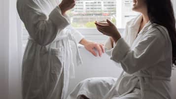 Una pareja con batas blancas sentada junto a una ventana con vistas a la ciudad.