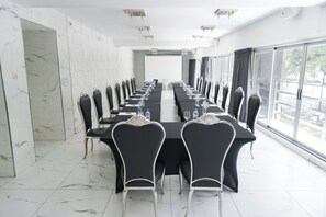 A conference room with a long table, chairs, and a projector screen. - Ker San Telmo Hotel (Buenos Aires)