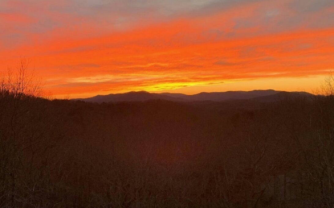 Tramonto su un paesaggio collinare con erba secca in primo piano.