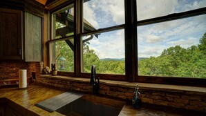 A rustic kitchen with a large window overlooking a forested landscape. - Luxury Cabin with amazing sunsets! Close to Downtown Blue Ridge! (Blue Ridge)