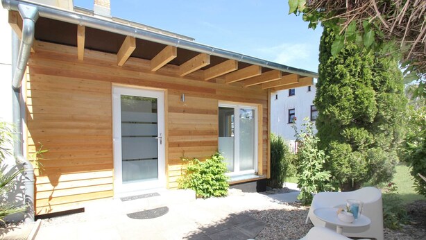 A wooden house with a covered patio, a small garden, and outdoor seating. - 01: 34 m², 2-room, 2 pers., Terrace, WL - Villa Elise in Ostseebad Göhren (Göhren)
