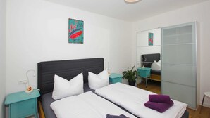 A modern hotel room with a large bed, a nightstand, a mirror, and a small table with a plant. - 01: 34 m², 2-room, 2 pers., Terrace, WL - Villa Elise in Ostseebad Göhren (Göhren)