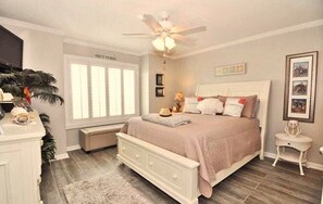 Un dormitorio con cama, mesita de noche y ventilador de techo.